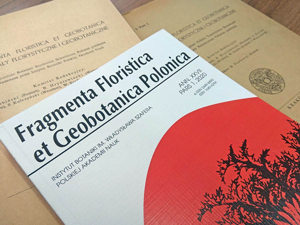 Three journal issues are laid out on the table. Two are yellowed from age. The third is newer; it has a white and red cover
